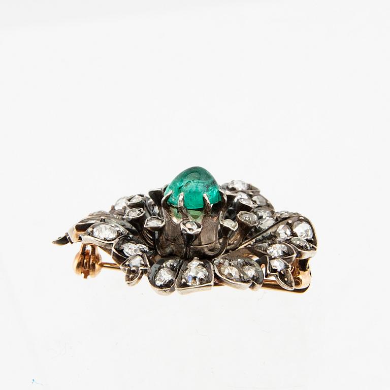A 14K gold brooch set with a cabochon-cut emerald and old-cut as well as rose-cut diamonds.