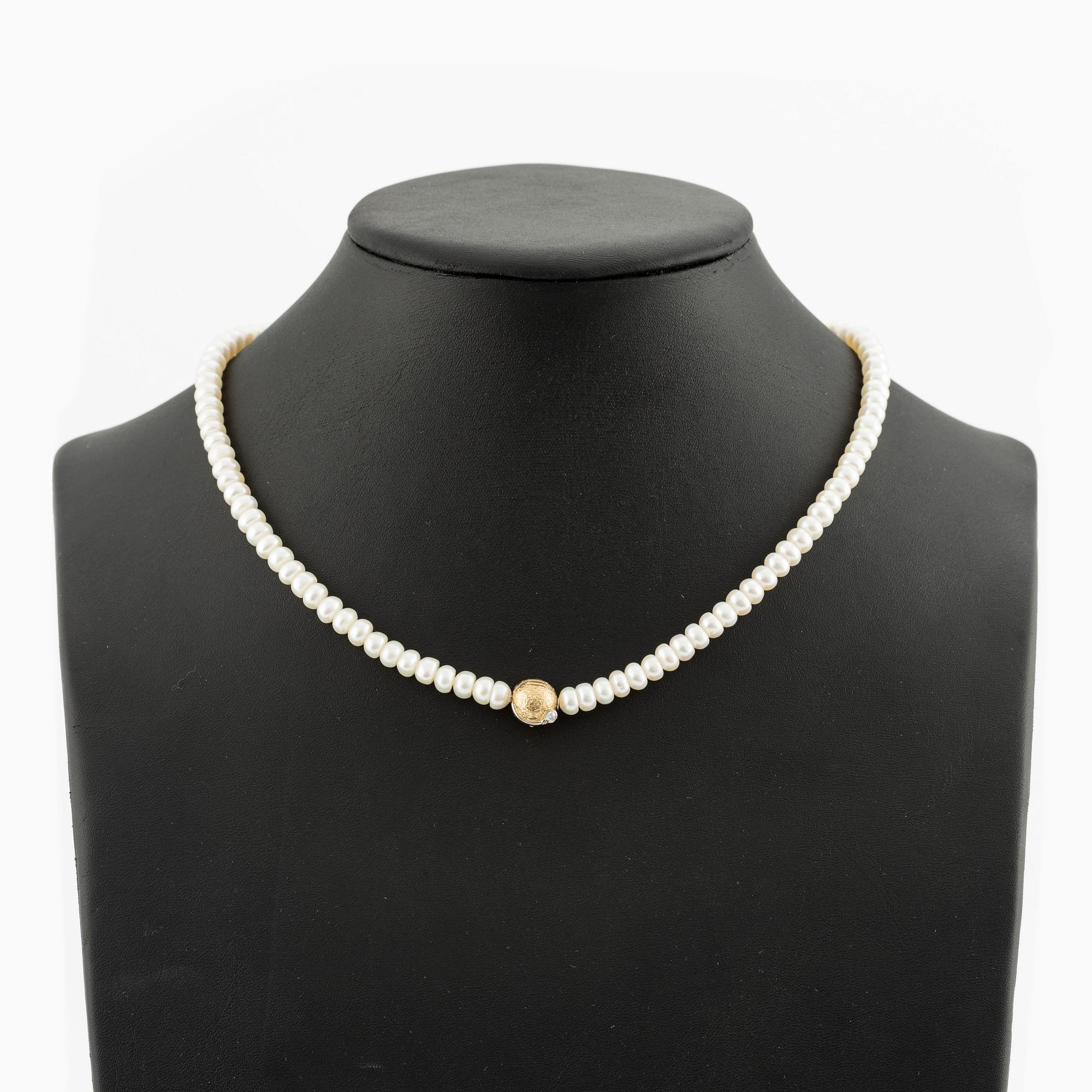 Ole Lynggaard clasp in 18K gold with a round brilliant-cut diamond and a freshwater cultured pearl necklace.
