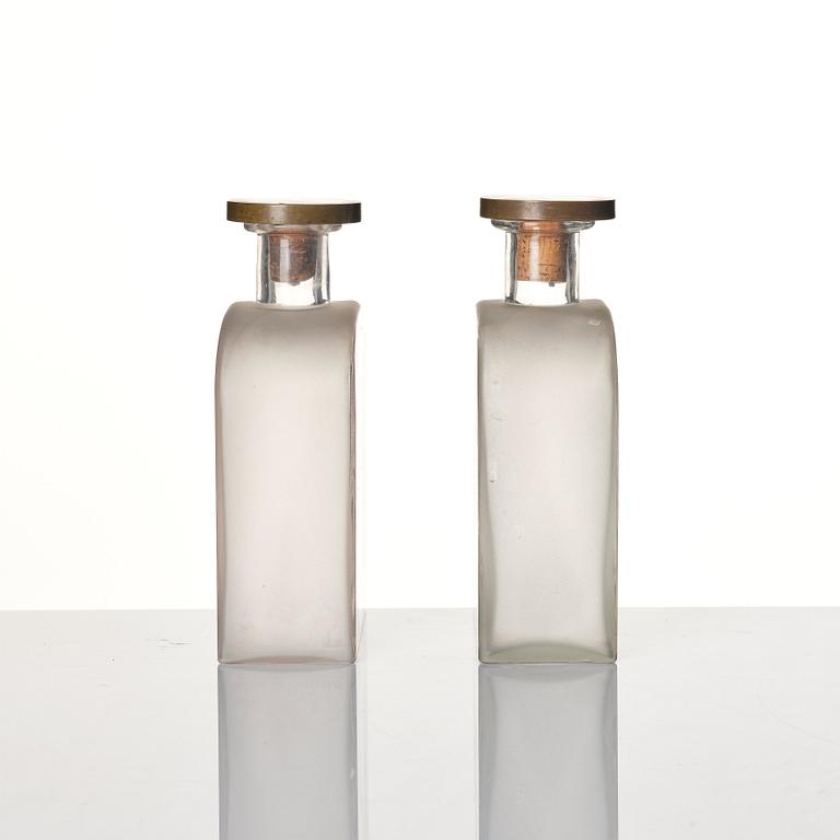 Firma Svenskt Tenn, a pair of glass bottles with pewter and brass stoppers designed by Björn Trägårdh, 1930s.