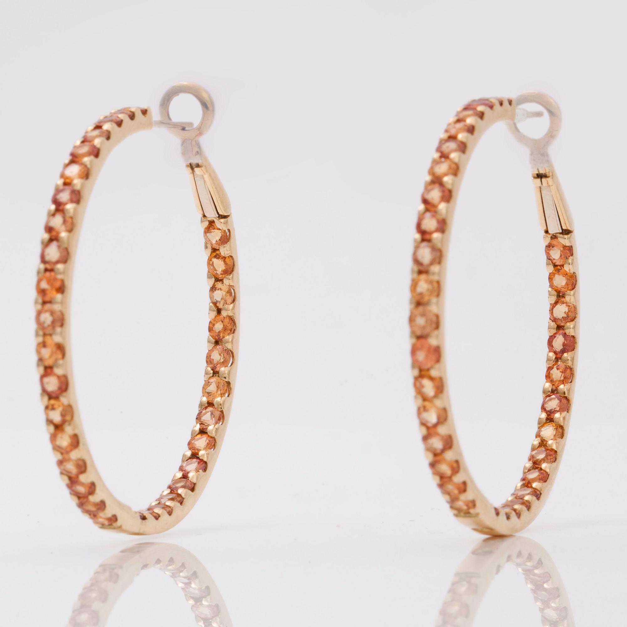 A pair of orange-yellow sapphire hoop earrings.