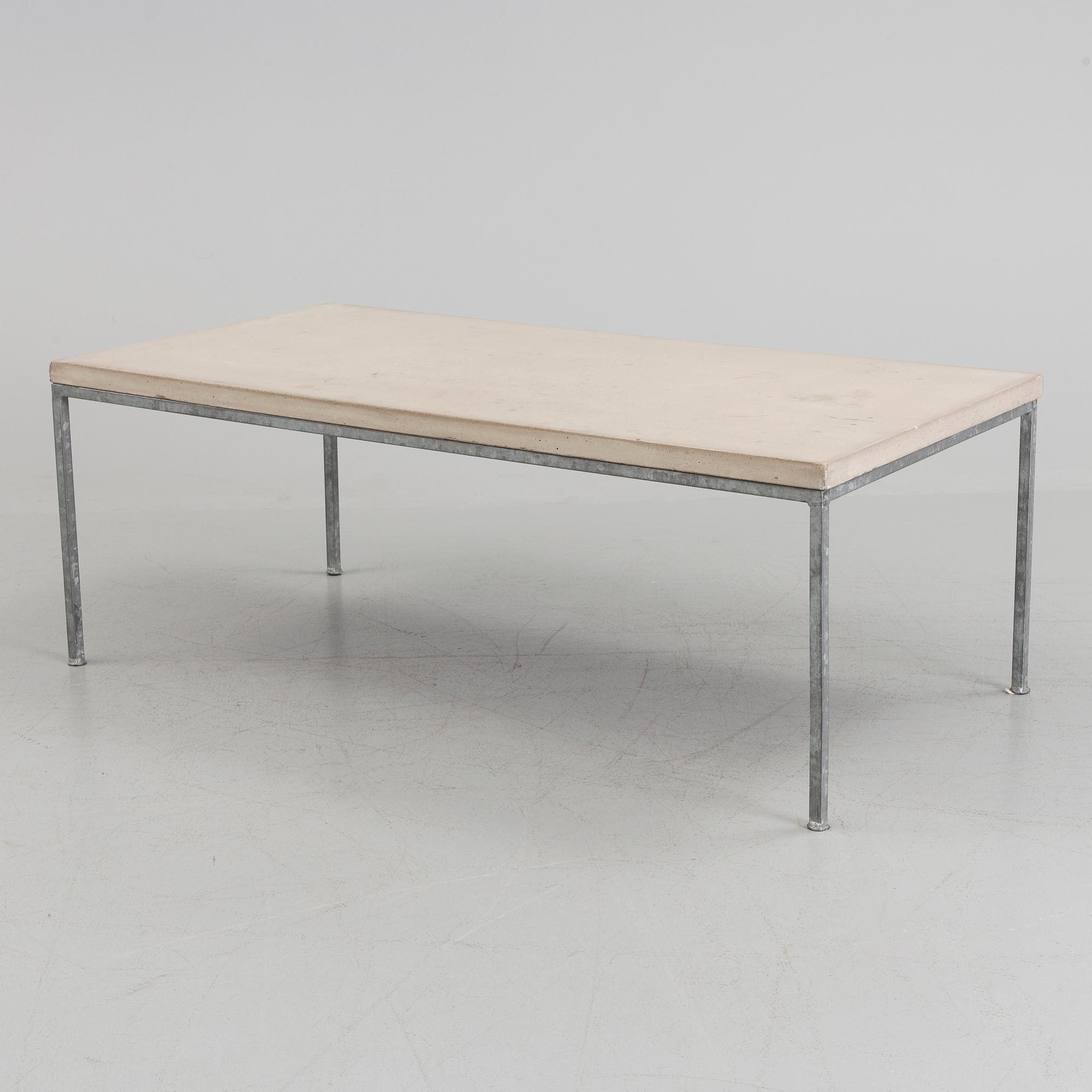 A modern sofa table with concrete top and steel legs.