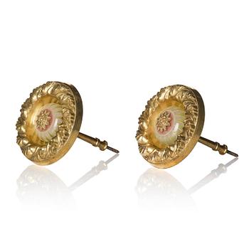 A pair of presumably English Empire repoussé gilt-brass and painted glass curtain tiebacks, early 19th century.