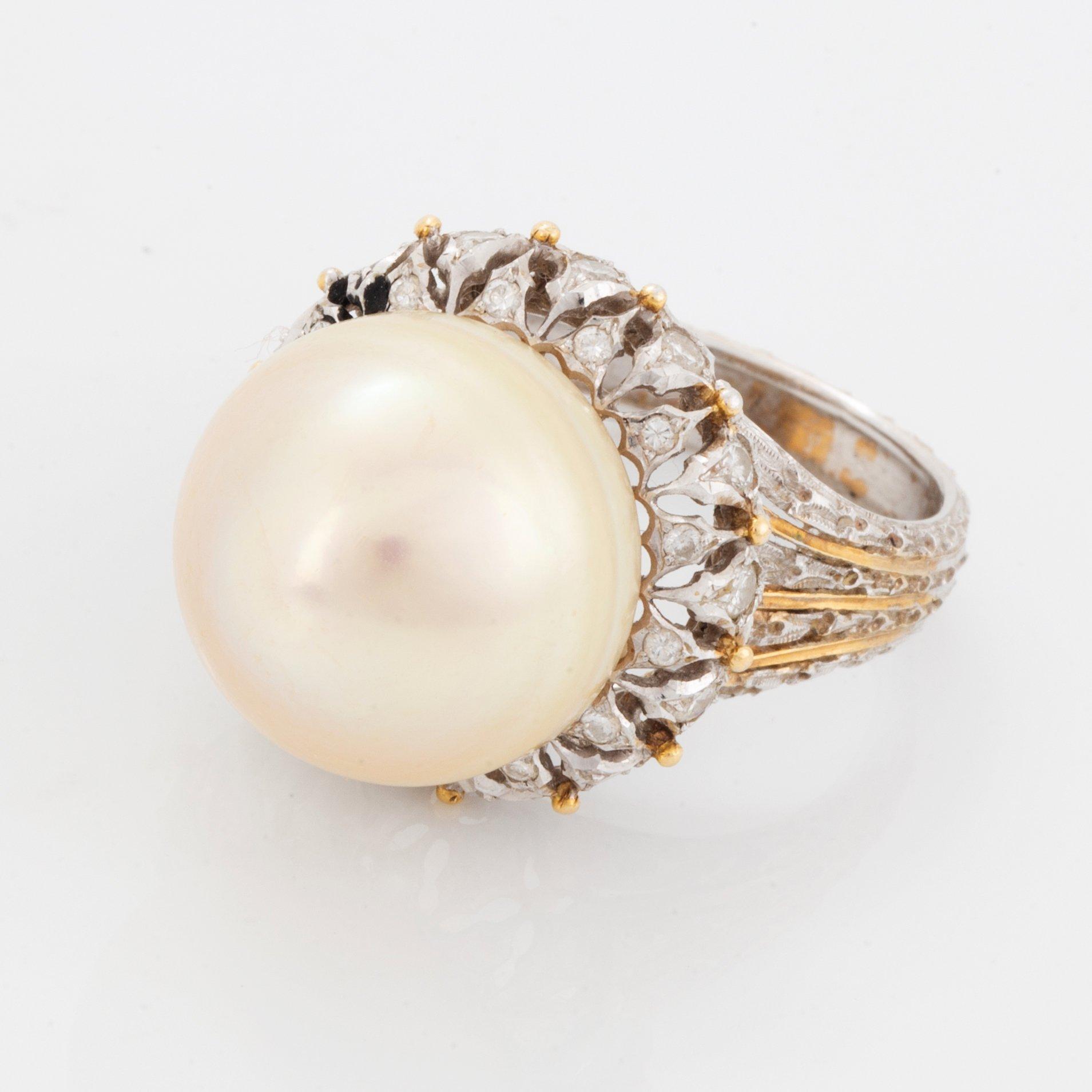 An 18K gold ring set with a cultured pearl and round brilliant-cut diamonds.