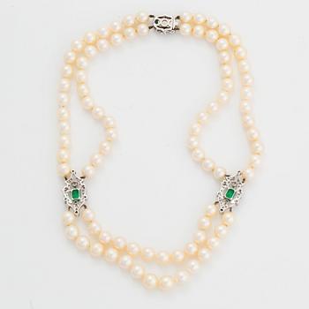 A two strand cultured pearl necklace clasp in 18K white gold set with a faceted emerald.