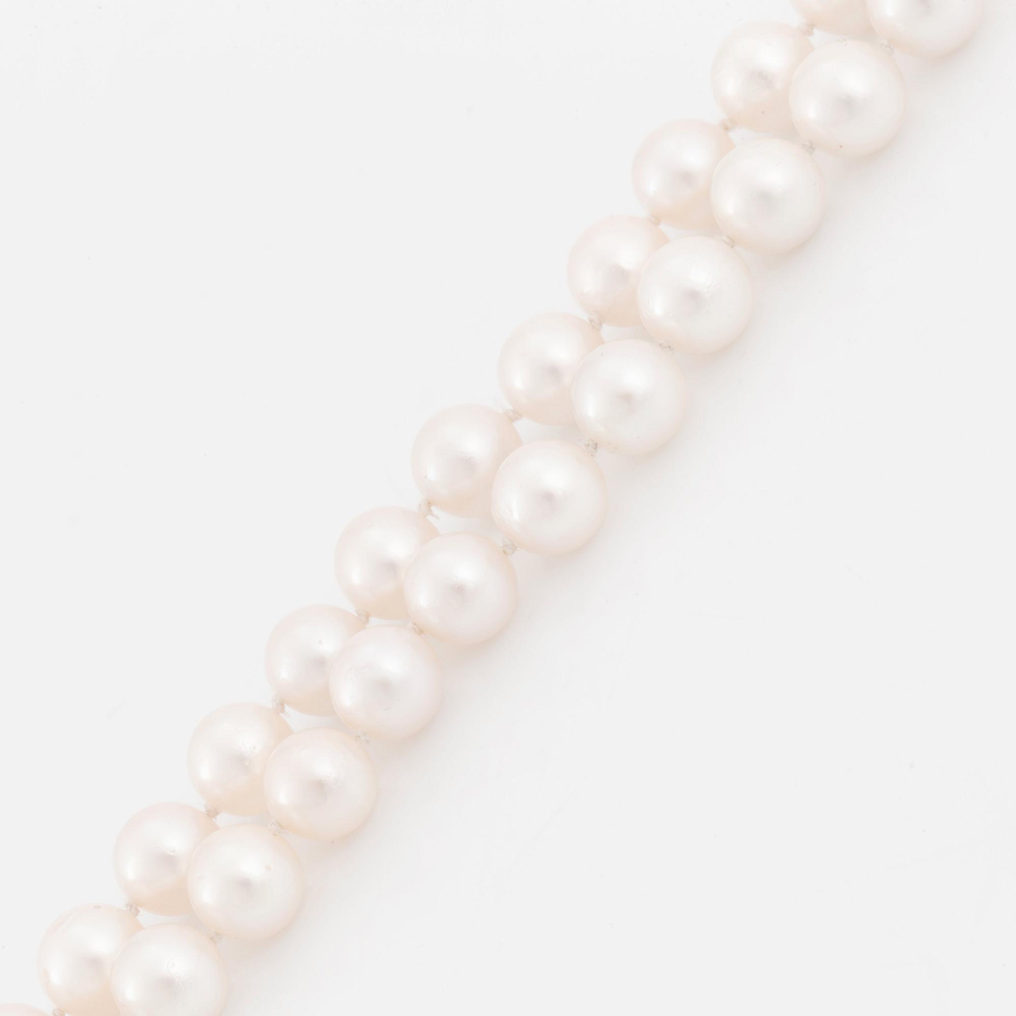 A cultured pearl necklace with a 14K white gold bow pendant set with round brillliant-cut diamonds.