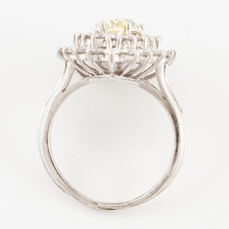 A platinum ring set with a pear-shaped yellow diamond and round brilliant-cut diamonds.