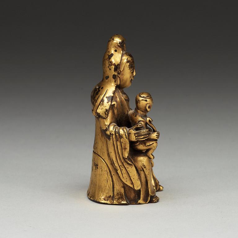 A seated gilt bronze figure of Guanyin with a small boy, Qing dynasty, 18th Century.