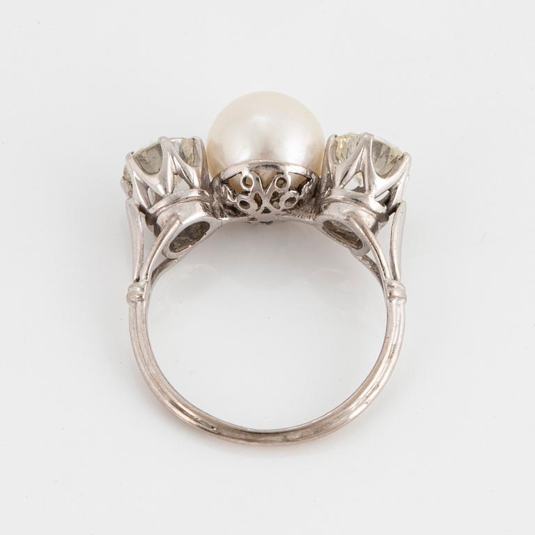 An 18K white gold ring set with a cultured pearl and two round brilliant-cut diamonds.