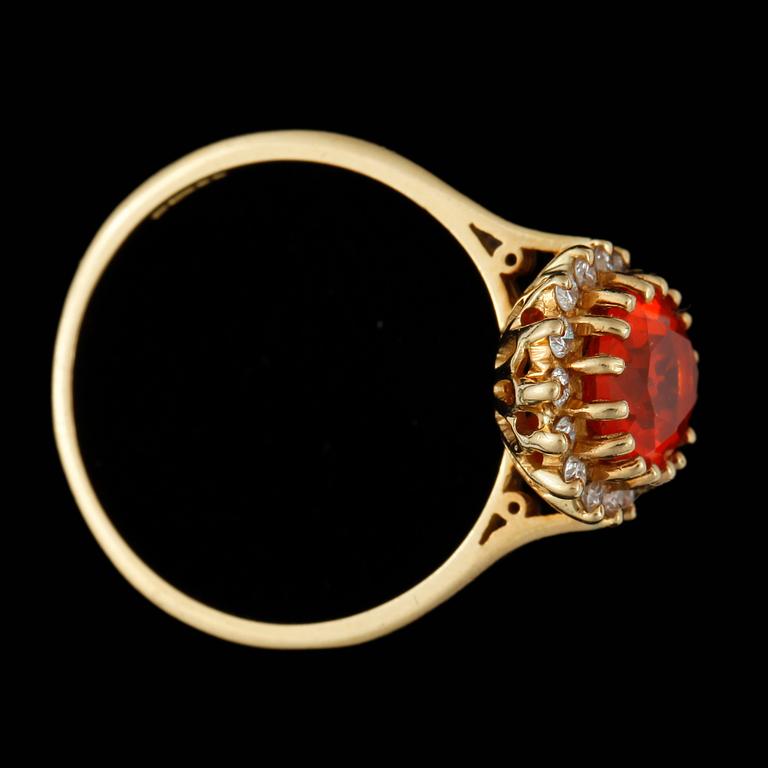 RING, 18k guld med eldopal och krans av 16 små briljantslipade diamanter, tot ca 0,16 ct. Vikt ca 4 gram.