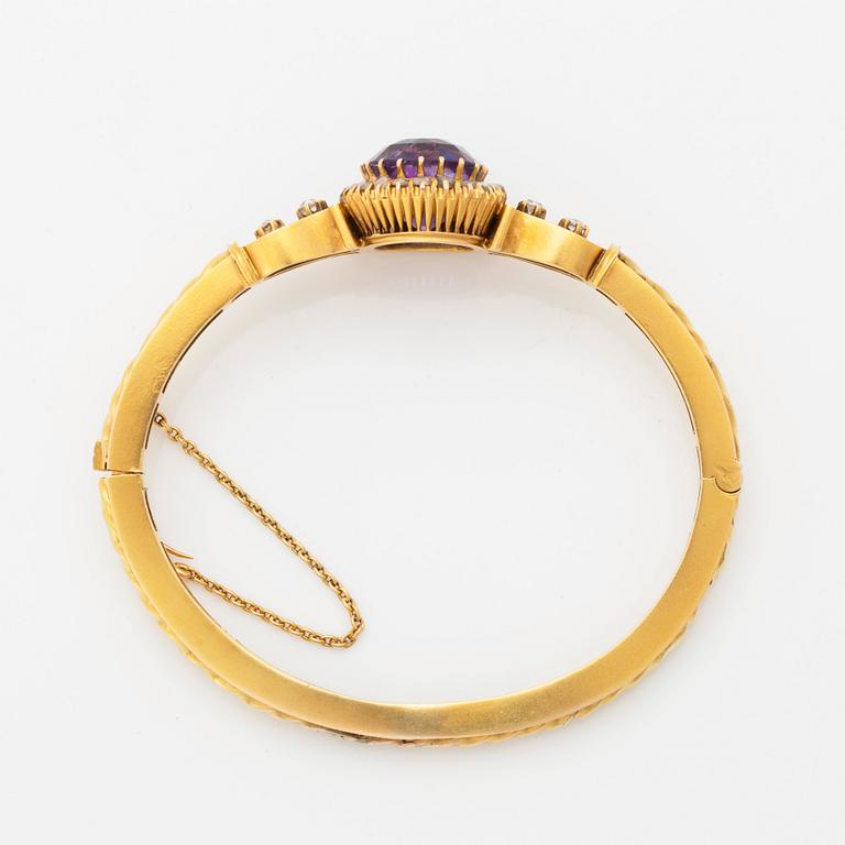 A 14K gold bangle set with a faceted amethyst and rose-and old-cut diamonds.