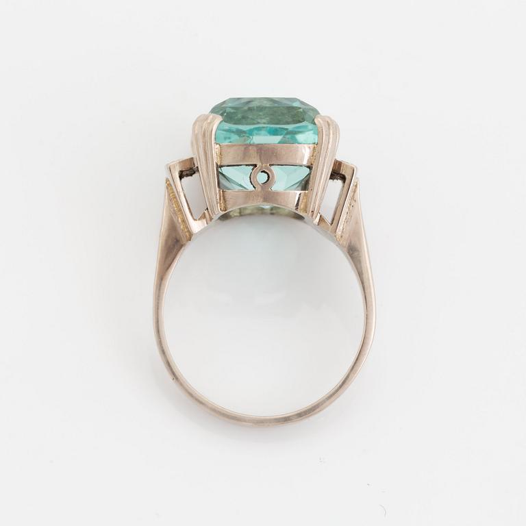 An 18K white gold ring set with a faceted aquamarine and round brilliant-cut diamonds.