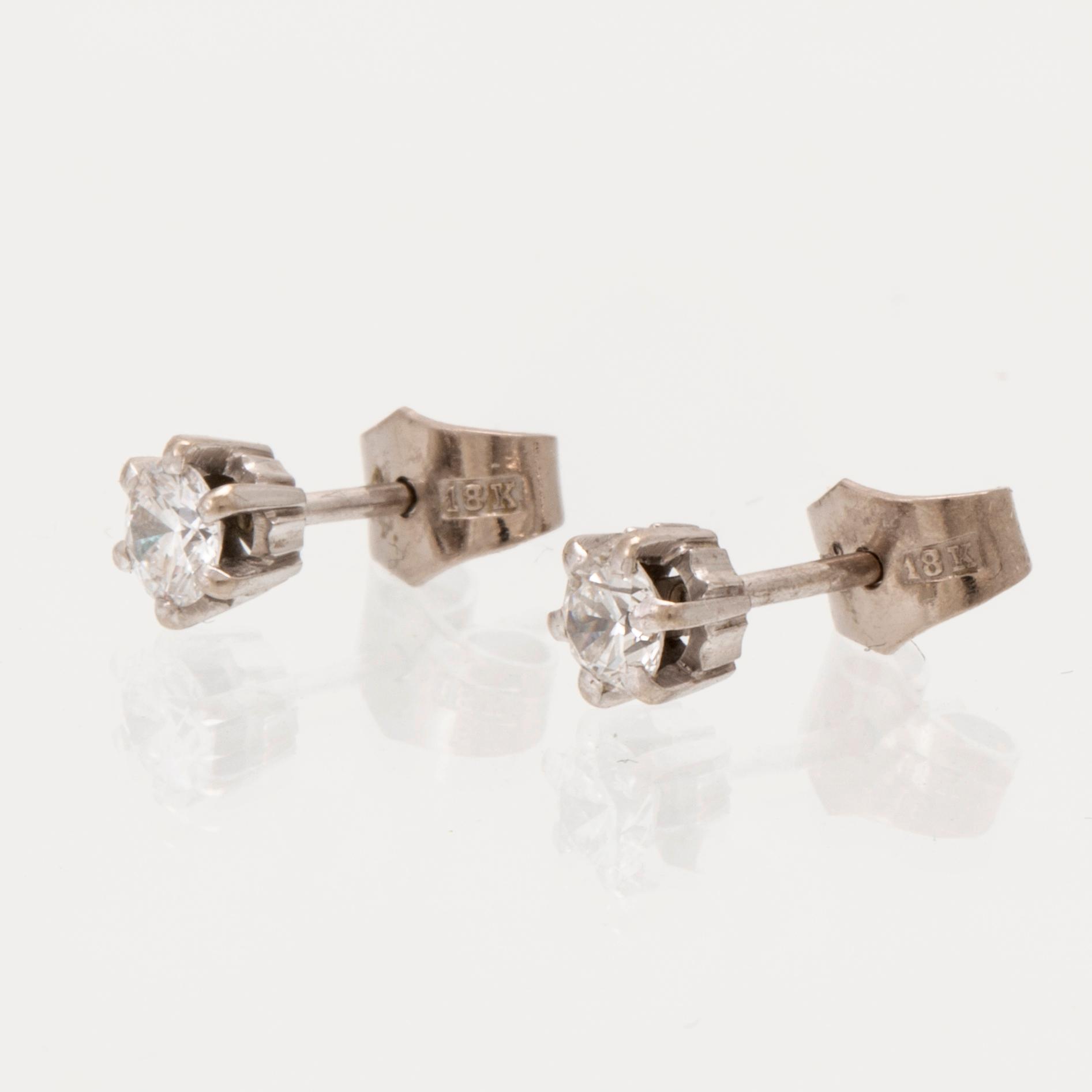 A pair of 18K white gold earrings set with round brilliant cut diamonds.