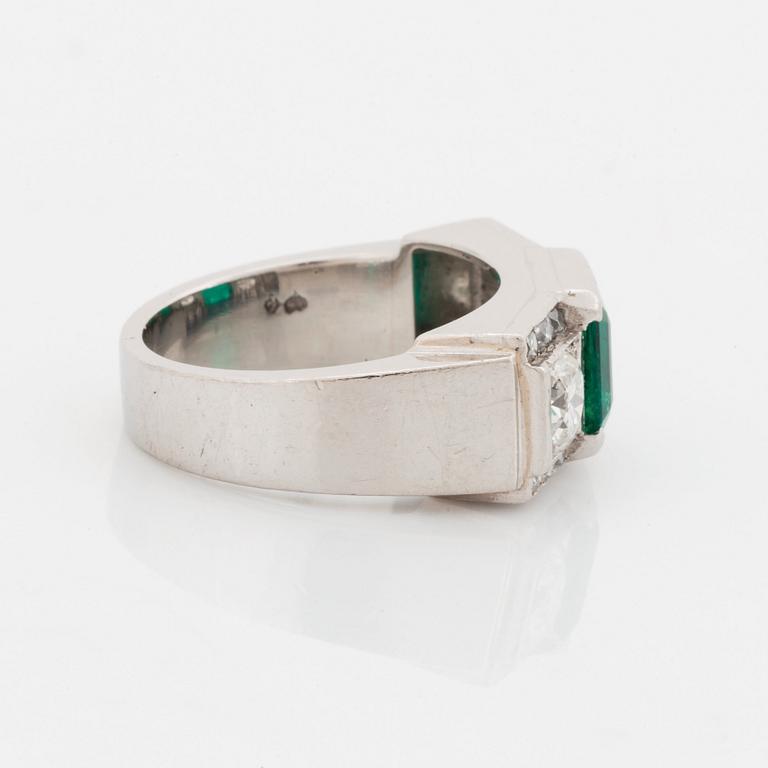 Ring platina med en trappslipad smaragd och runda briljant- och fasettslipade diamanter.