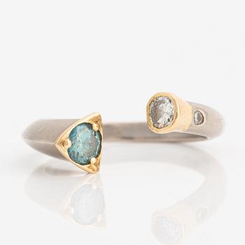 Ring in 18K gold with two round brilliant-cut diamonds and one color-treated blue diamond.