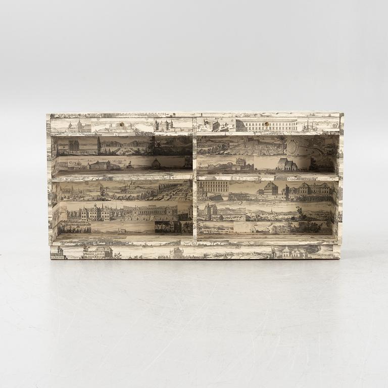 A bookcase decorated in prints from Dahlbergs Suecia antiqua et hodierna, mid 20th century.