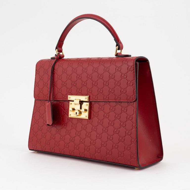 Gucci, a red, embossed leather handbag.