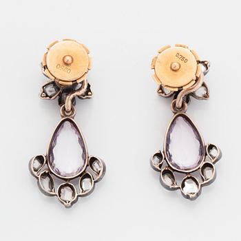 Ett par örhängen silver och guld med fasettslipad droppformad rosa topas.
