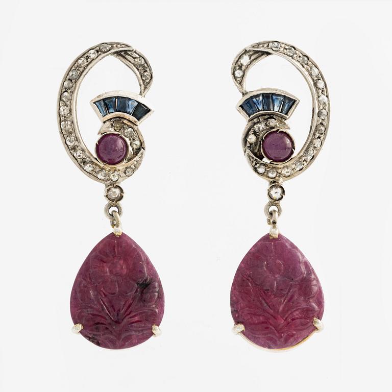 Silver earrings with carved rubies featuring floral motifs, sapphires, and rose-cut diamonds.