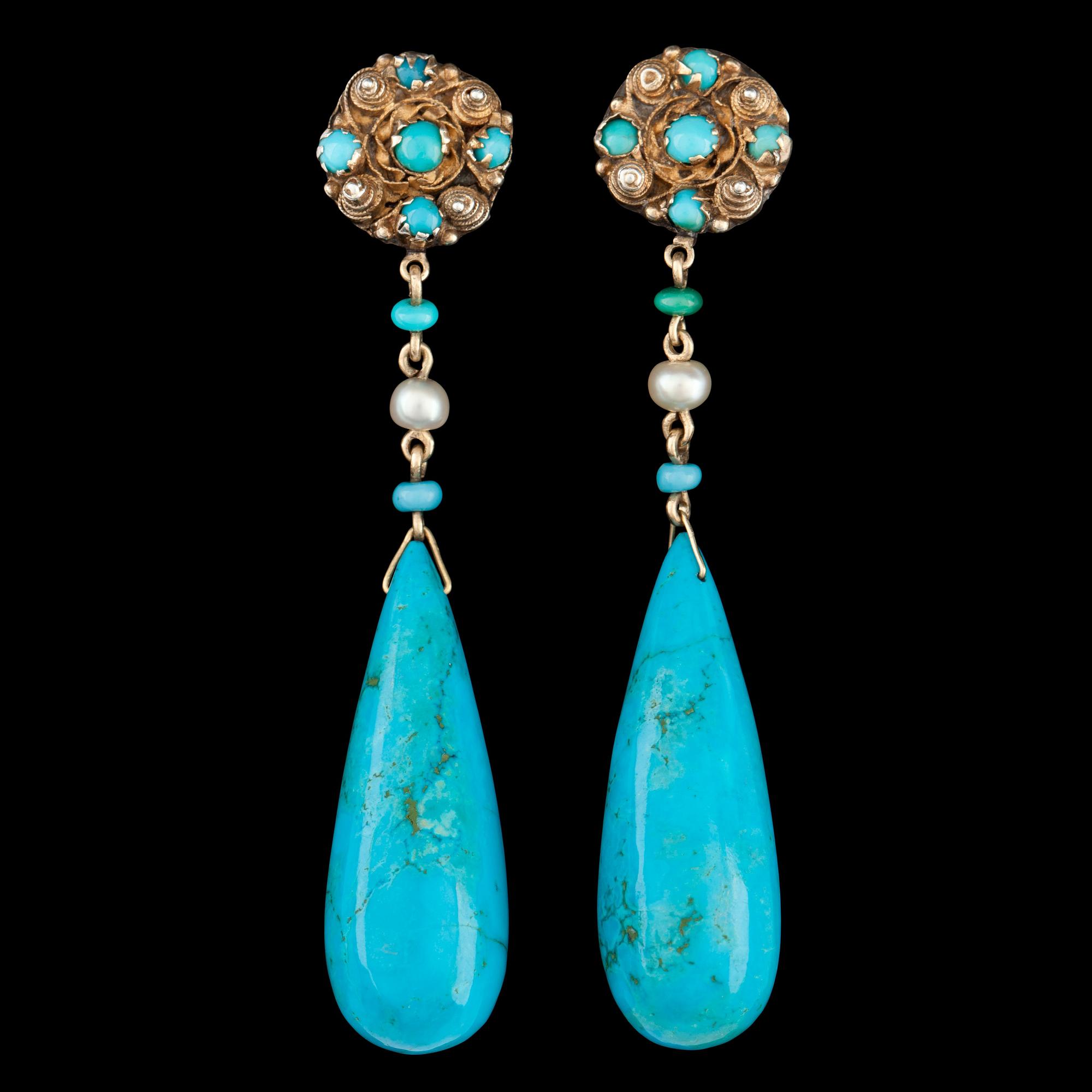 A pair of drop shaped turqouise earrings.