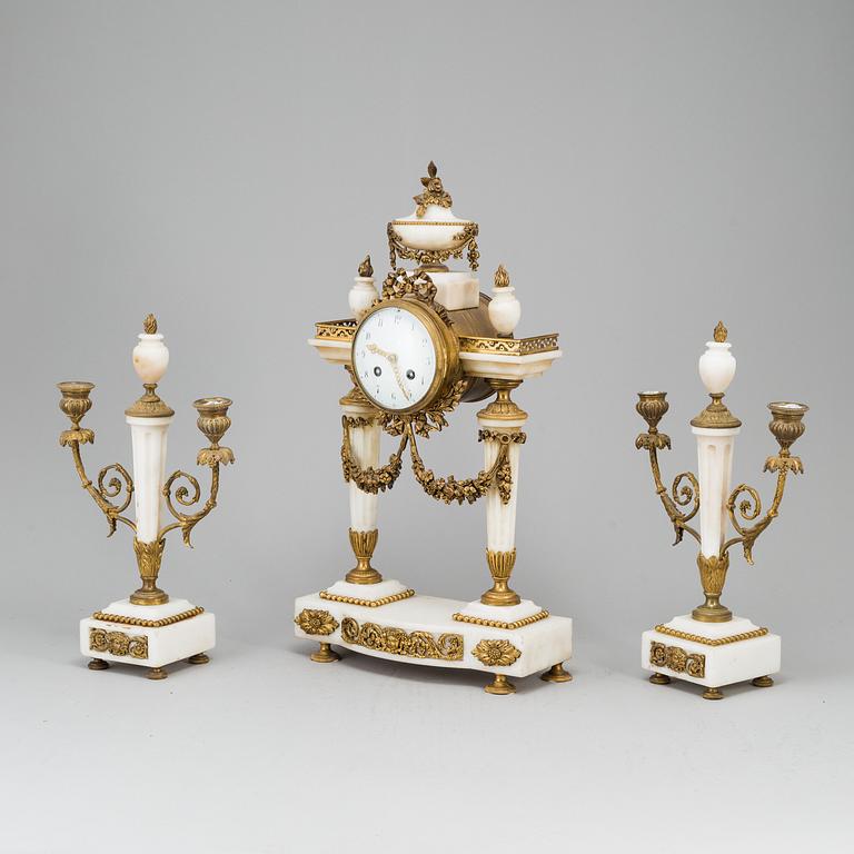 A Louis XVI-style mantle clock and a pair of candelabras. Early 20th century.