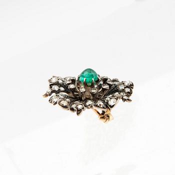 A 14K gold brooch set with a cabochon-cut emerald and old-cut as well as rose-cut diamonds.