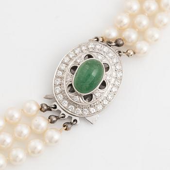 Three-row pearl necklace with cultured pearls, clasp with cabochon-cut emerald and brilliant-cut diamonds.
