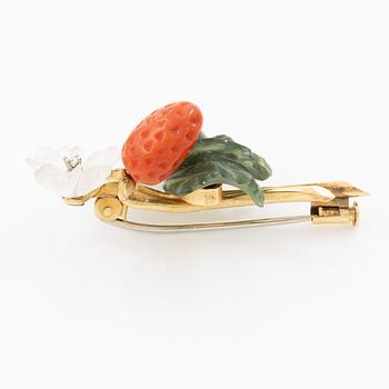 A flower brooch 18K gold with coral, rock crystal, a green stone likely nephrite, and a round brilliant-cut diamond.