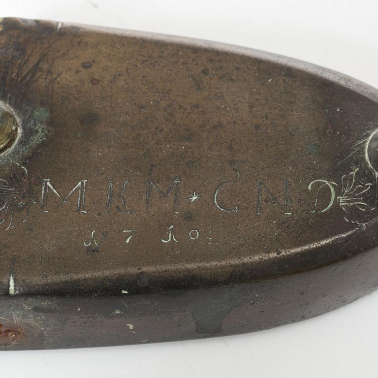 A brass clothes iron, dated 1710.