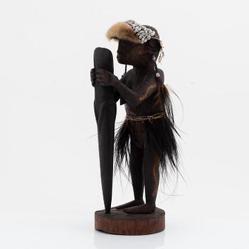 An Asmat carving of a woman holding an ax, Yamas, Jeni, 20th Century.