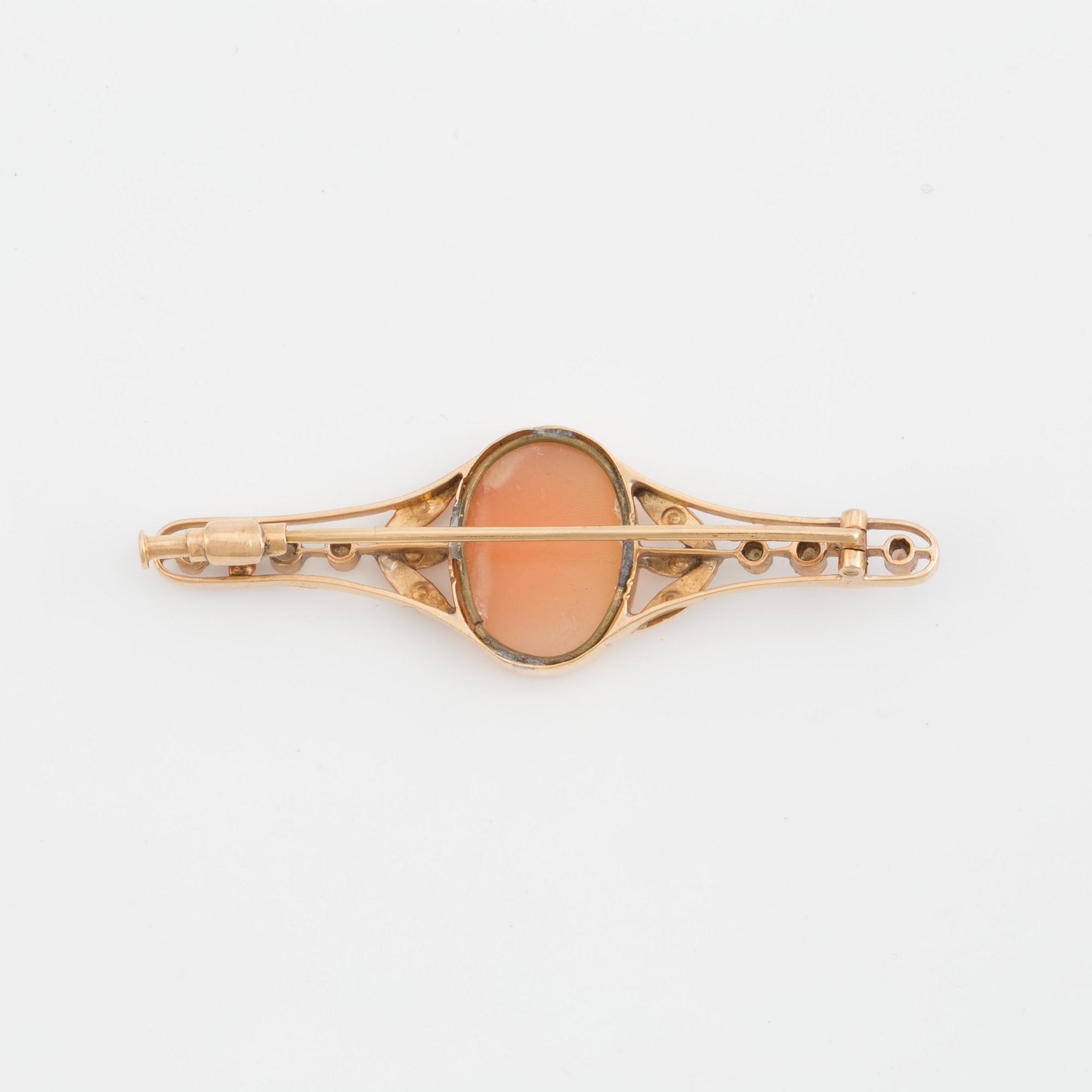 A brooch set with a shell cameo, seed pearls and probably synthetic rubies.