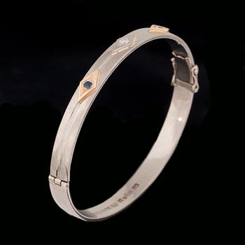 ARMRING, 18 k vitguld med briljantslipad diamant ca 0.05 ct samt 2 fasettslipade safirer. Vikt ca 33 g.