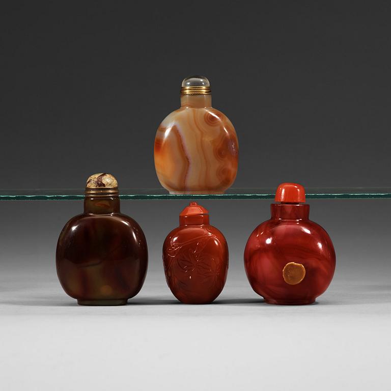 A set of four glass and stone snuff bottles with stoppers.