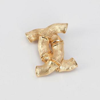 CHANEL, a gold colored brooch.