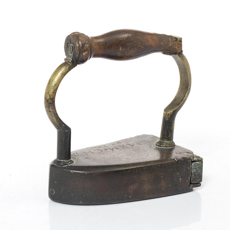 A brass clothes iron, dated 1710.