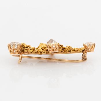 A gold brooch set with old-cut diamonds and an uncut diamond.