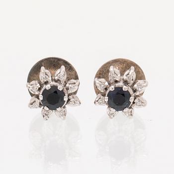 A pair of 8K white gold earrings set with single cut diamonds and round brilliant cut blue gemstones.