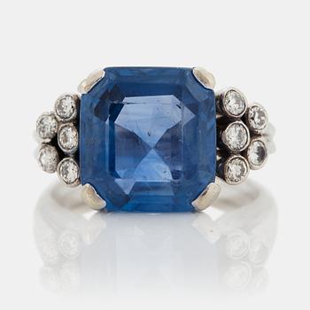 1037. An 18K white gold ring set with a faceted sapphire and round brilliant-cut diamonds.