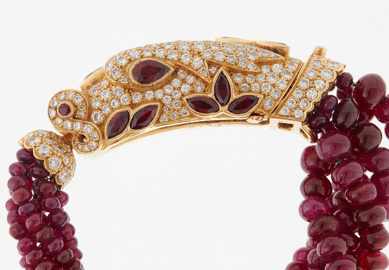 A Cartier chimera head bracelet in 18K gold set with round brilliant-cut diamonds and faceted rubies.