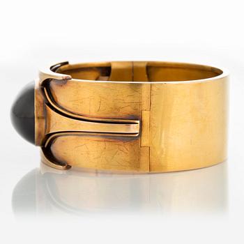 A 14K gold bangle set with a cabochon-cut garnet.