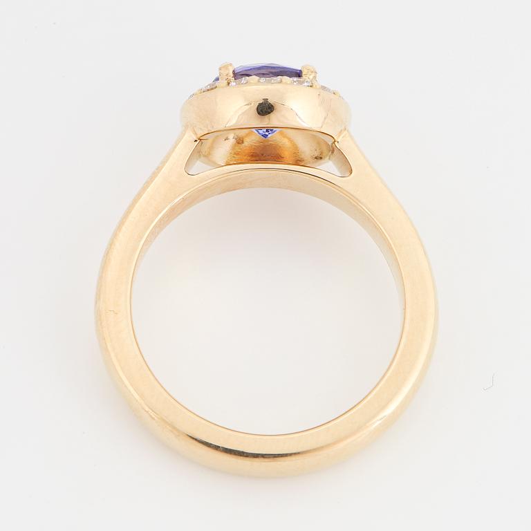 An 18K gold ring set with a faceted tanzanite and round brilliant-cut diamonds.