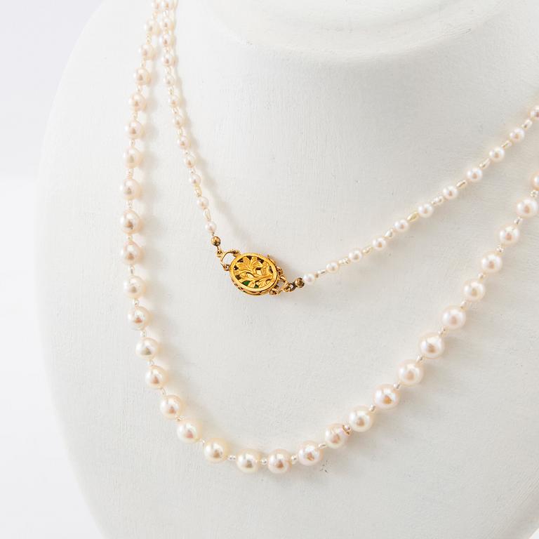 Necklace of cultured pearls with a clasp of 18K gold and cabochon-cut green stone.
