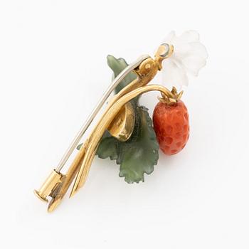 A flower brooch 18K gold with coral, rock crystal, a green stone likely nephrite, and a round brilliant-cut diamond.