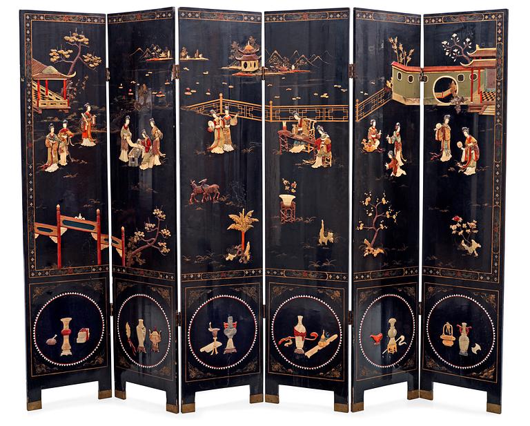 A chinese black lacquer six-panel screen, early 20th Century, with figures in gardens, inlays of carved mother of pearl, coloured bone, tree, and different stones. Back of panels with flowers painted in gold.