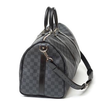 A black damier ebene canvas weekend bag by Louis Vuitton.