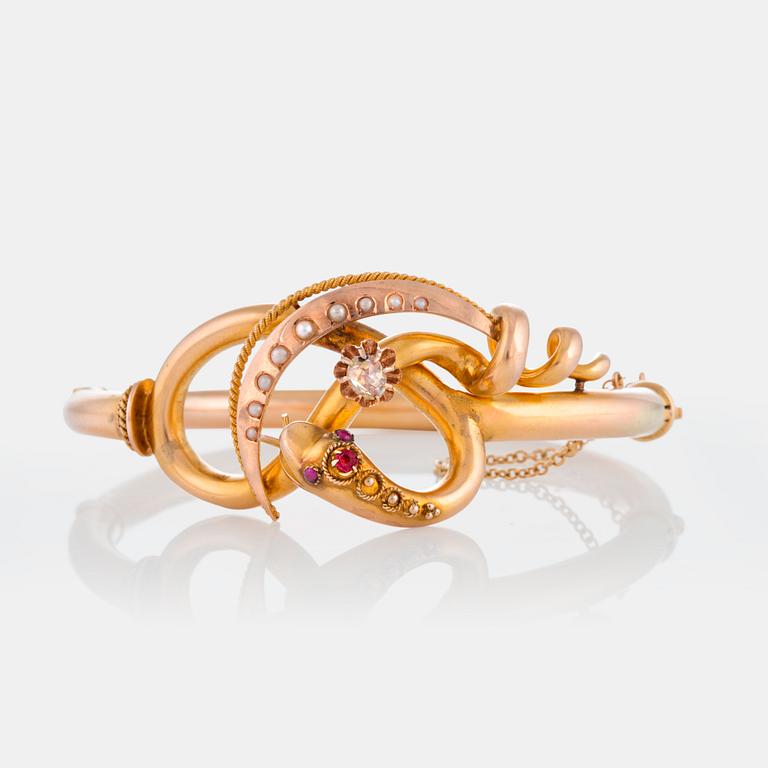 A snake bangle in 14K gold set with a rose-cut diamond, pearls and cabochon-cut rubies.