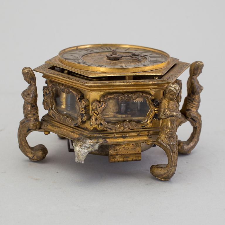 A gilded brass baroque travel clock from around 1700, with original case.