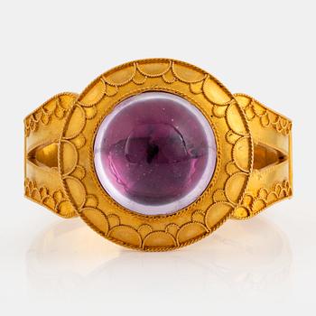 1026. An 18K gold bracelet set with a cabochon-cut amethyst.