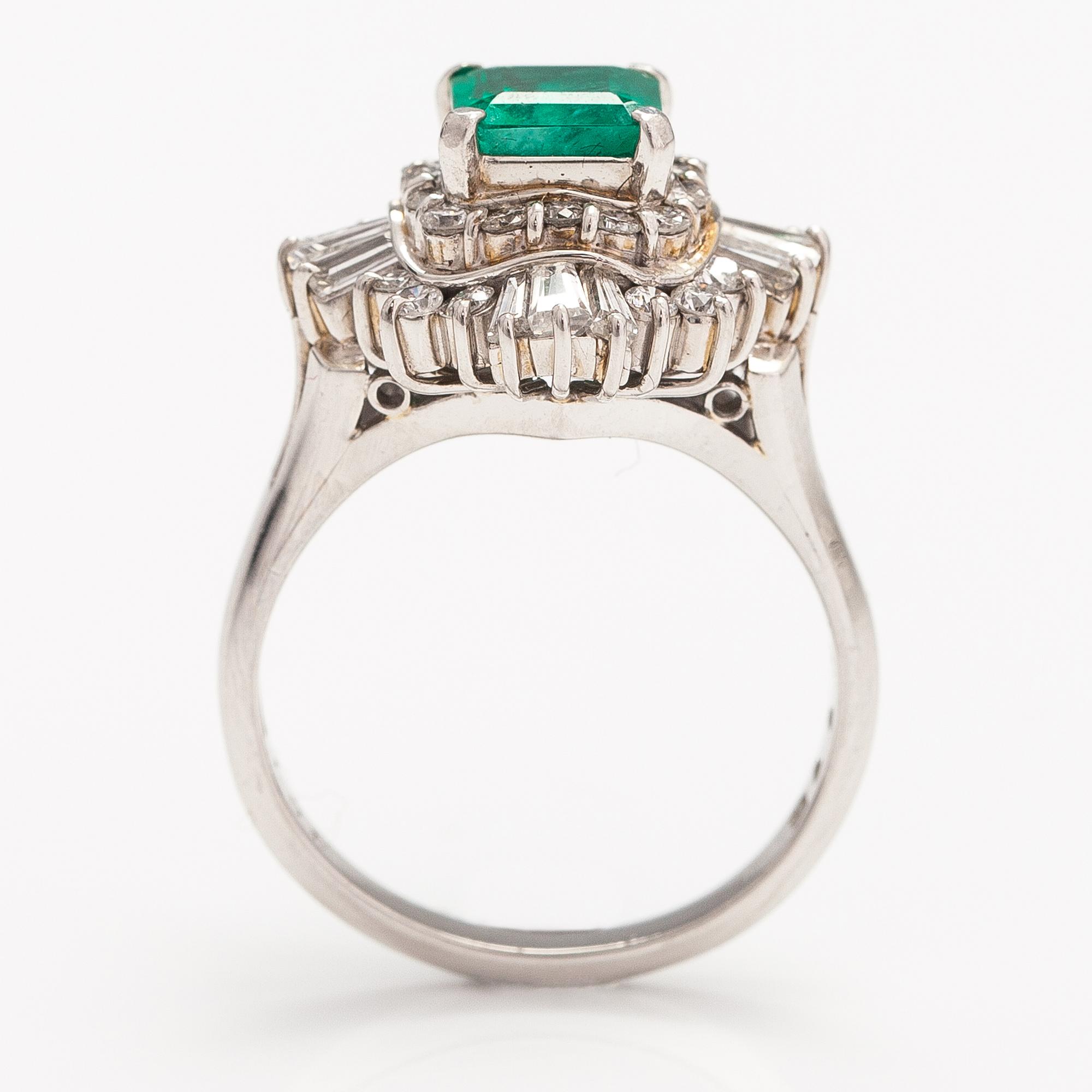 A platinum ring with a ca. 1.15 ct emerald and ca. 1.00 cts of diamonds in total.