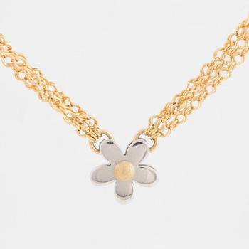 A three stranded chain necklace with a pendant in the shape of a flower.