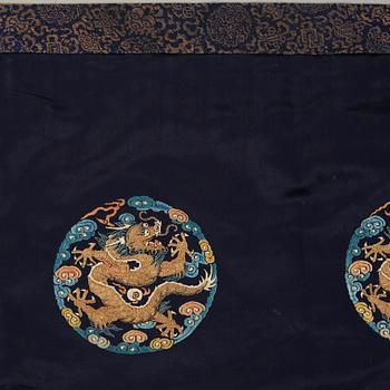 AN ALTAR DRAPE, embroidered silk. A fragment. China late Qing dynasty. 66,5 x 213-231,5 cm.